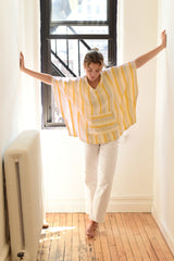 yellow-ivory-poncho on model with white jeans in hallway