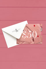 Home & Loft Valentine's Day Gift Card for $50 on a pink wooden background