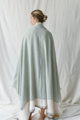 Sage green blanket with visible thin stripes on model