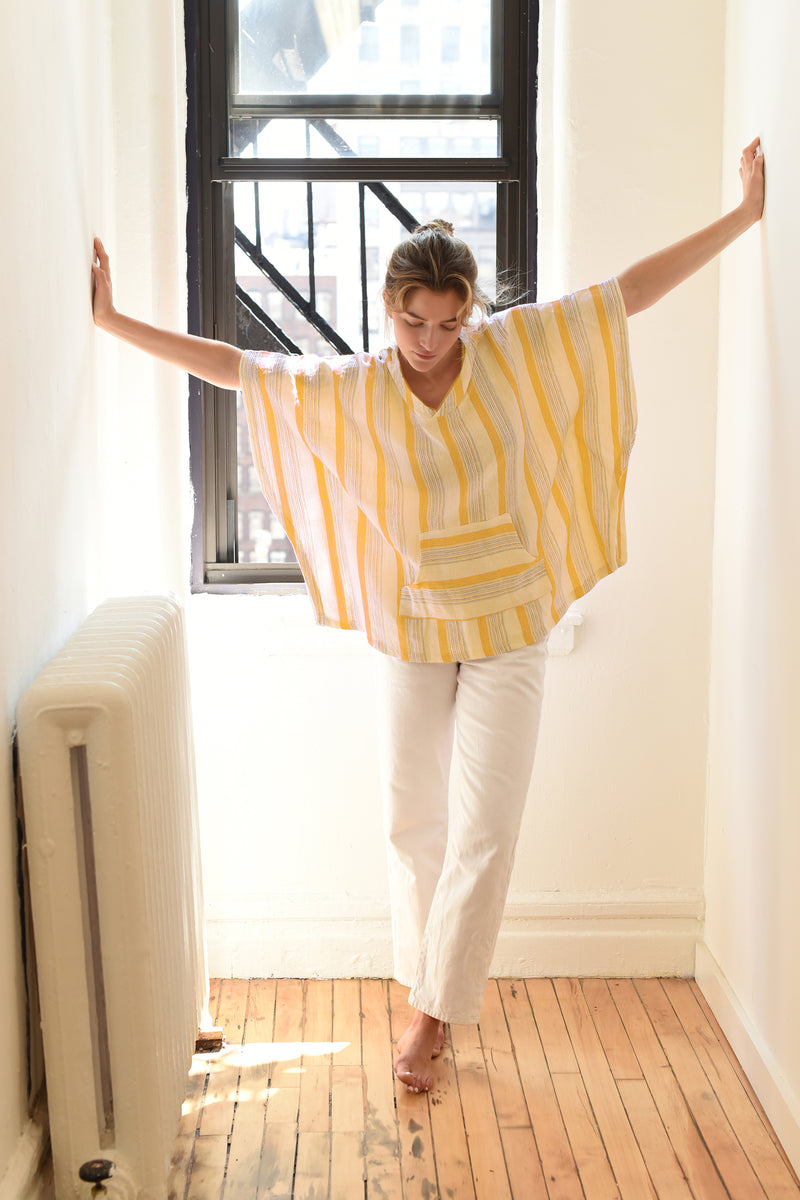yellow-ivory-poncho on model with white jeans in hallway